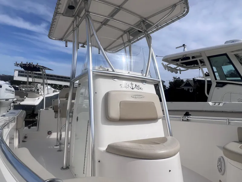 Slide: The Image of 2014 Cobia 201 Center Console boat with T-top, docked under a clear blue sky. - 14