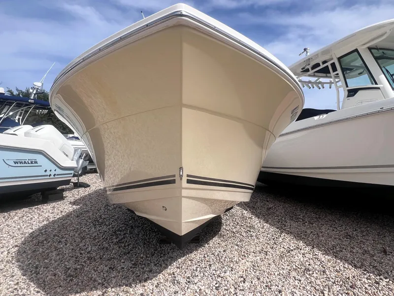 Slide: The Image of 2014 Cobia 201 Center Console boat on gravel, front view, clear sky background. - 2