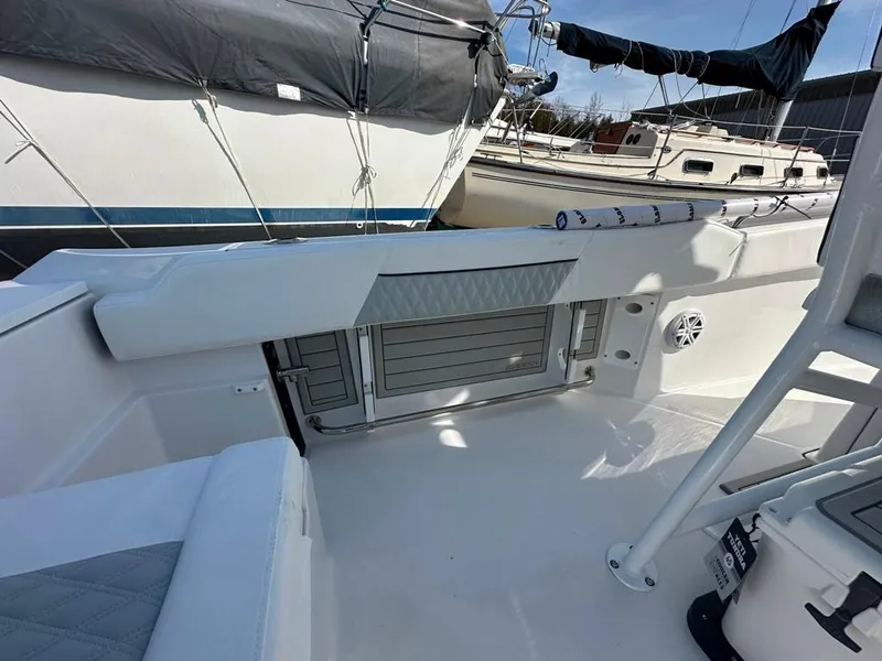 Slide: The Image of 2024 Blackfin 222CC boat interior with seating and storage, docked near other boats. - 15