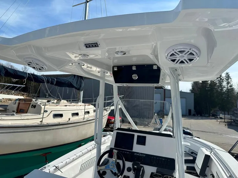 Slide: The Image of 2024 Blackfin 222CC boat console with speakers and navigation equipment, docked near other boats. - 17