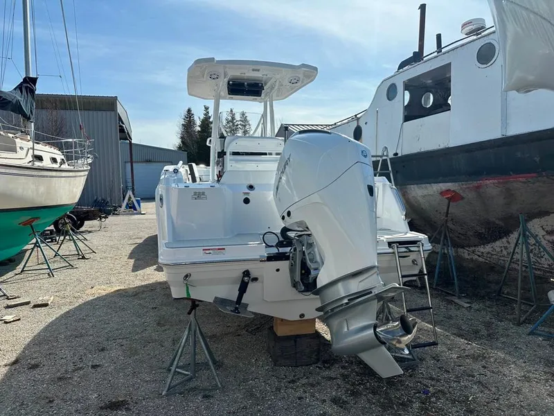 Slide: The Image of 2024 Blackfin 222CC boat with outboard motor, docked in a boatyard. - 2