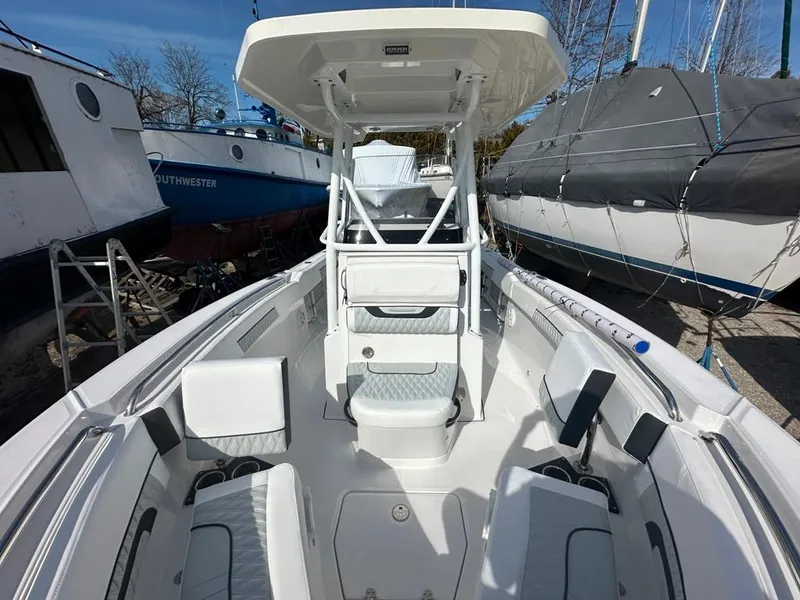 Slide: The Image of 2024 Blackfin 222CC boat interior with seating and console, docked among other boats. - 27