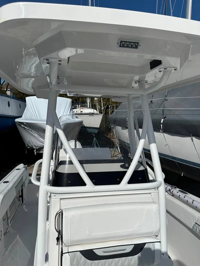 Slide: The Image of 2024 Blackfin 222CC boat interior with T-top and seating, docked in a marina. - 28