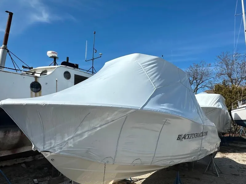 Slide: The Image of 2024 Blackfin 222CC boat covered in protective wrap, docked outdoors under clear blue sky. - 36