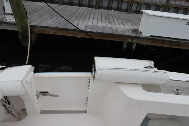 Slide: The Image of 2007 Cabo 40 Hardtop Express boat interior near dock, featuring white seating and storage compartments. - 12