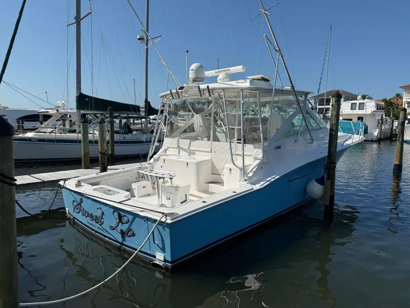 Slide: The Image of 2007 Cabo 40 Hardtop Express boat docked in marina, blue and white exterior. - 2