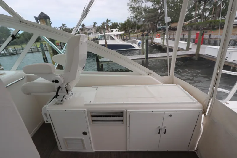Slide: The Image of 2007 Cabo 40 Hardtop Express boat interior with seating and storage, docked at marina. - 24