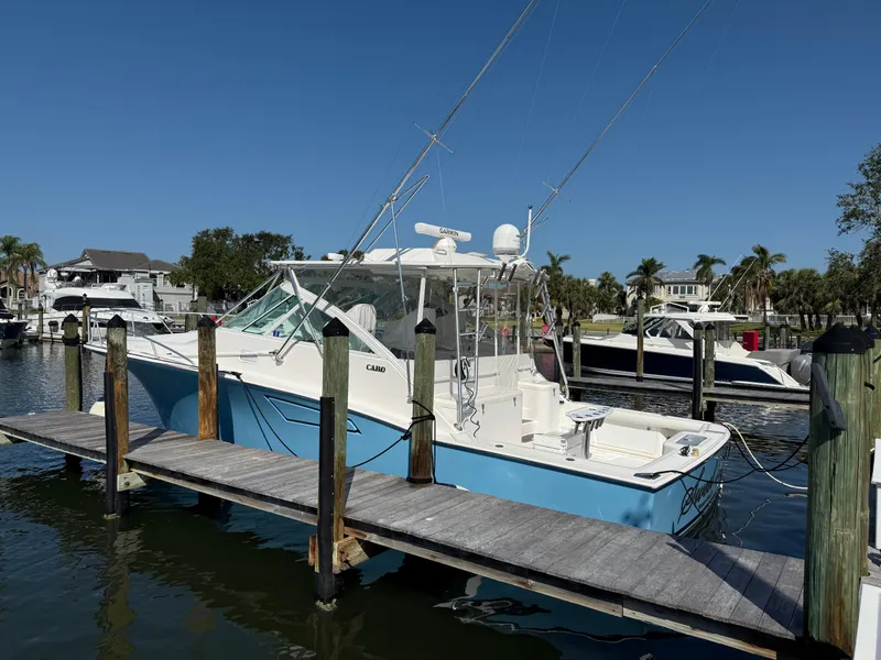 Slide: The Image of 2007 Cabo 40 Hardtop Express boat docked at marina, clear sky, palm trees in background. - 4