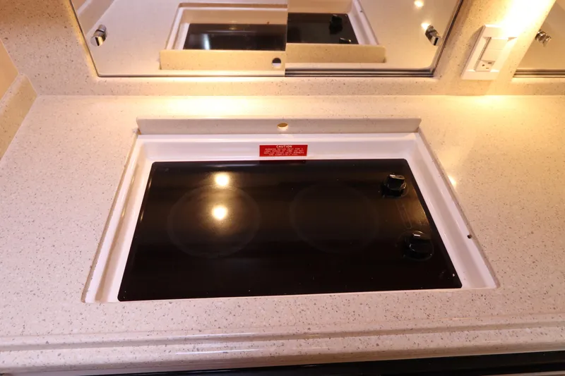 Slide: The Image of 2007 Cabo 40 Hardtop Express kitchen with sleek electric cooktop and mirrored backsplash. - 42
