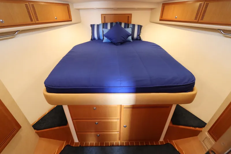 Slide: The Image of Luxurious cabin interior of 2007 Cabo 40 Hardtop Express with blue bedding and wooden storage. - 46