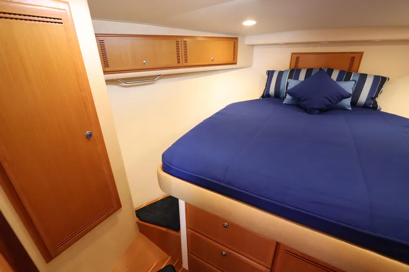 Slide: The Image of Luxurious cabin interior of 2007 Cabo 40 Hardtop Express with blue bedding and wooden storage. - 47
