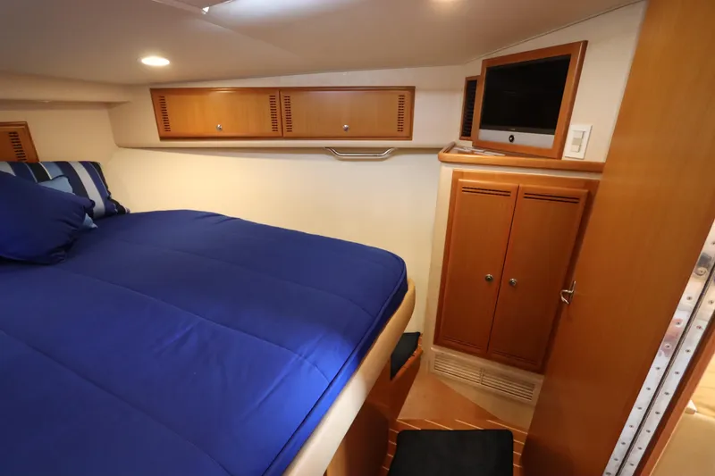 Slide: The Image of Interior cabin of 2007 Cabo 40 Hardtop Express with blue bedding and wooden cabinetry. - 48