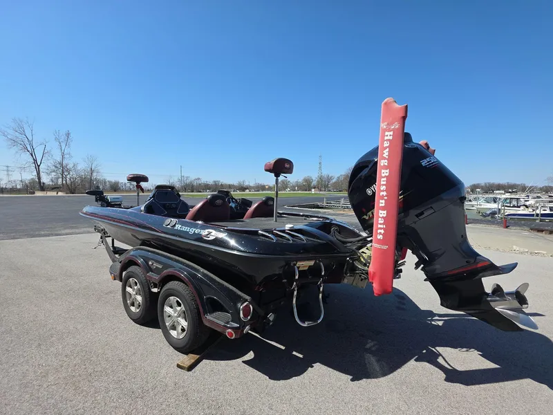 Slide: The Image of 2011 Ranger Z521 Comanche boat with motor on trailer, parked outdoors under clear blue sky. - 2