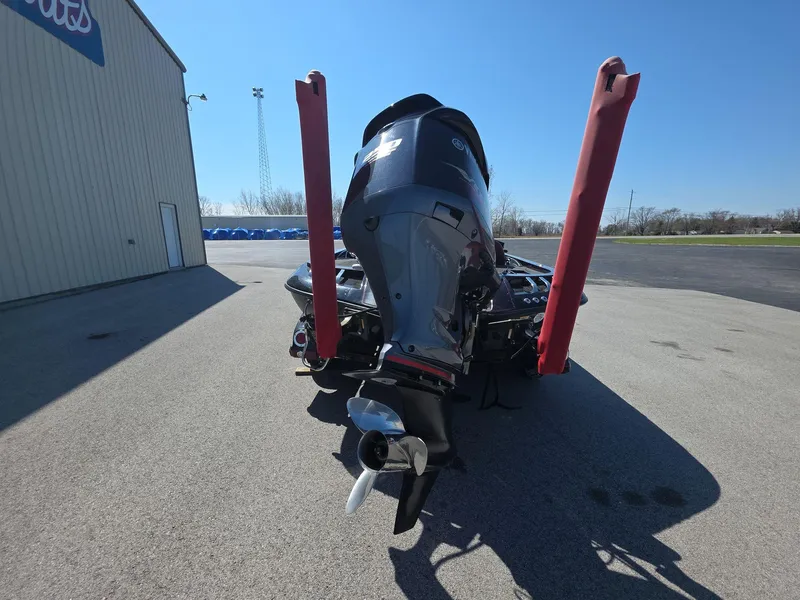 Slide: The Image of 2011 Ranger Z521 Comanche boat with outboard motor, parked on concrete near a building. - 3