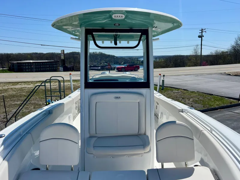 Slide: The Image of 2023 Sea Hunt Ultra 265 SE boat interior with seating and console, parked outdoors. - 21