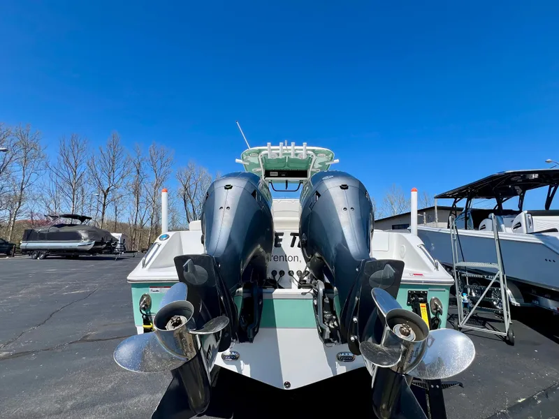 Slide: The Image of 2023 Sea Hunt Ultra 265 SE boat with dual engines, parked outdoors under clear blue sky. - 26
