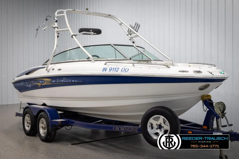 Slide: The Image of 2005 Crownline 216 LS boat on trailer in showroom, white and blue design. - 2