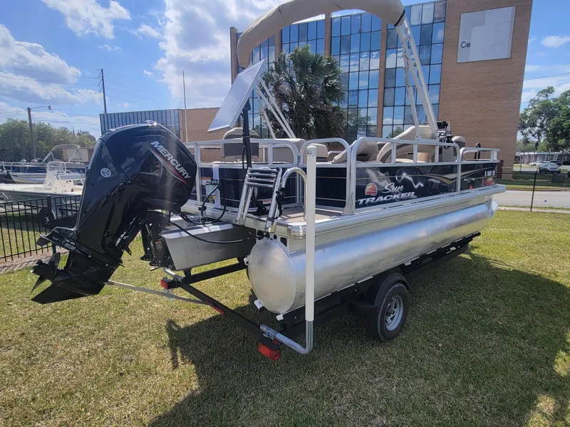 Slide: The Image of 2023 Sun Tracker Bass Buggy 18 DLX pontoon boat on trailer, parked on grass. - 3
