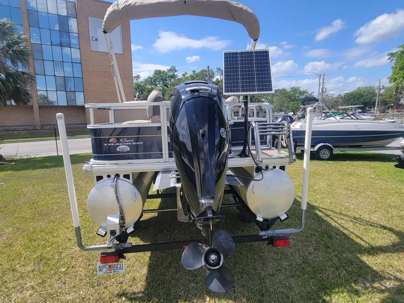 Slide: The Image of 2023 Sun Tracker Bass Buggy 18 DLX pontoon boat with solar panel, parked on grass. - 4