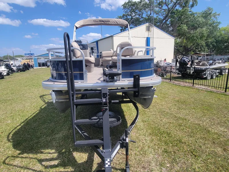 Slide: The Image of 2023 Sun Tracker Bass Buggy 18 DLX pontoon boat on trailer, parked on grass. - 5