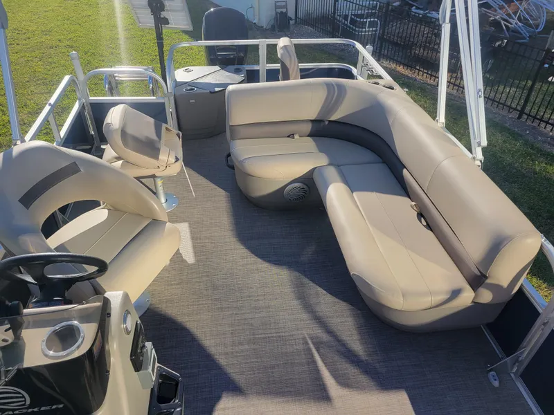 Slide: The Image of 2023 Sun Tracker Bass Buggy 18 DLX pontoon boat interior with beige seating and steering console. - 8