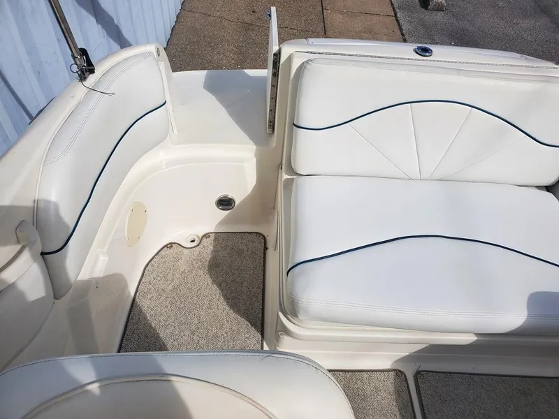 Slide: The Image of 1998 Sea Ray 210 Sundeck interior with white cushioned seating and carpeted flooring. - 12