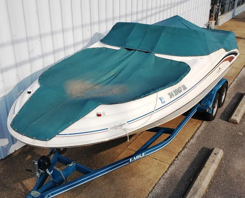 Slide: The Image of 1998 Sea Ray 210 Sundeck boat with teal cover on trailer, parked outdoors. - 27