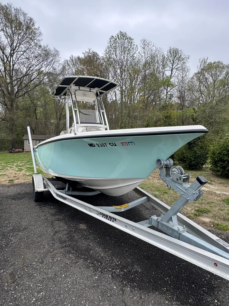 Slide: The Image of 2023 Key West 203 FS boat on trailer, parked outdoors, surrounded by trees. - 2