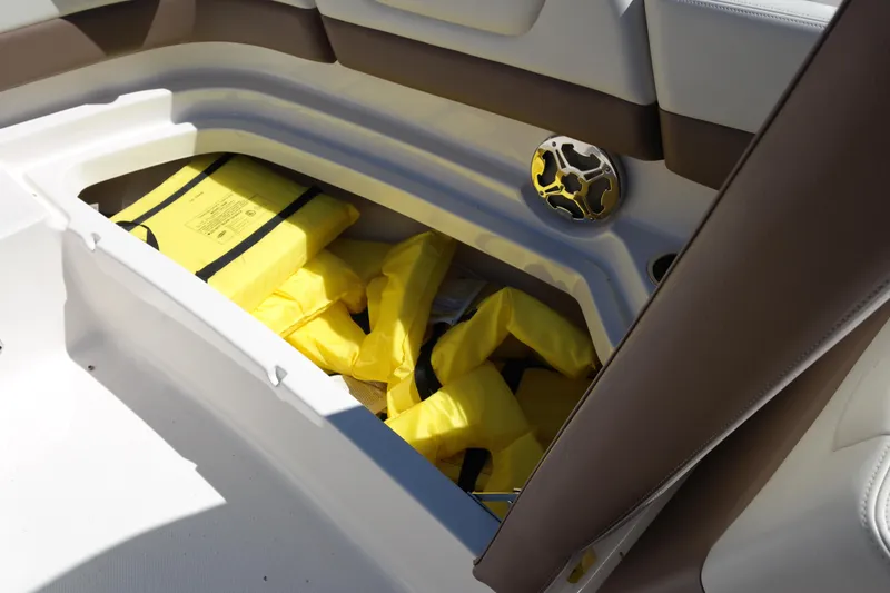 Slide: The Image of Storage compartment with yellow life jackets in a 2015 Chaparral 250 Suncoast boat. - 10