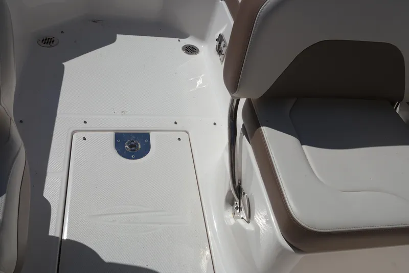Slide: The Image of 2015 Chaparral 250 Suncoast boat interior with white seating and storage compartment. - 28