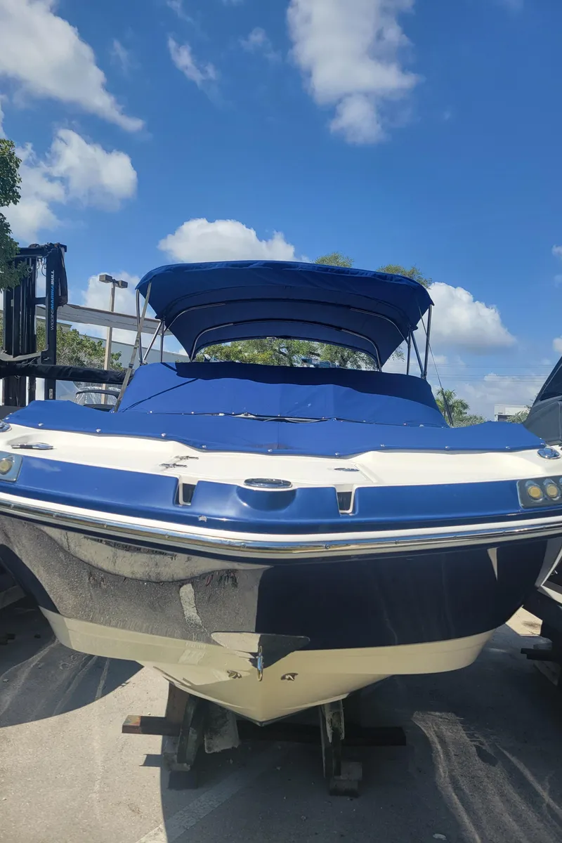 Slide: The Image of 2015 Chaparral 250 Suncoast boat with blue canopy, parked outdoors under a clear sky. - 36