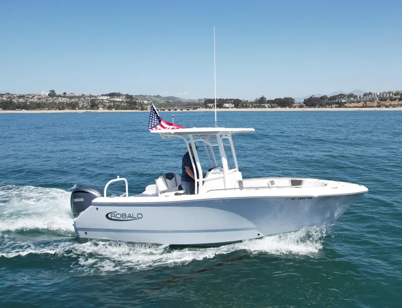 Slide: The Image of 2022 Robalo R230 Center Console boat cruising on open water with American flag. - 0
