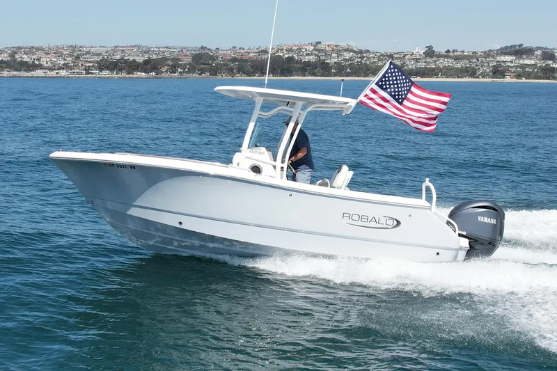 Slide: The Image of 2022 Robalo R230 Center Console boat cruising with American flag on open water. - 1