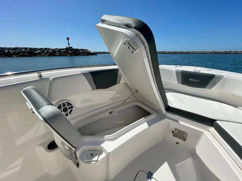 Slide: The Image of 2022 Robalo R230 Center Console boat with open storage compartment, docked by the water. - 10