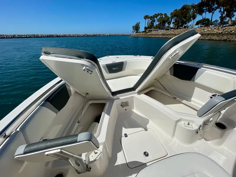 Slide: The Image of 2022 Robalo R230 Center Console boat with open storage compartments on calm water. - 11