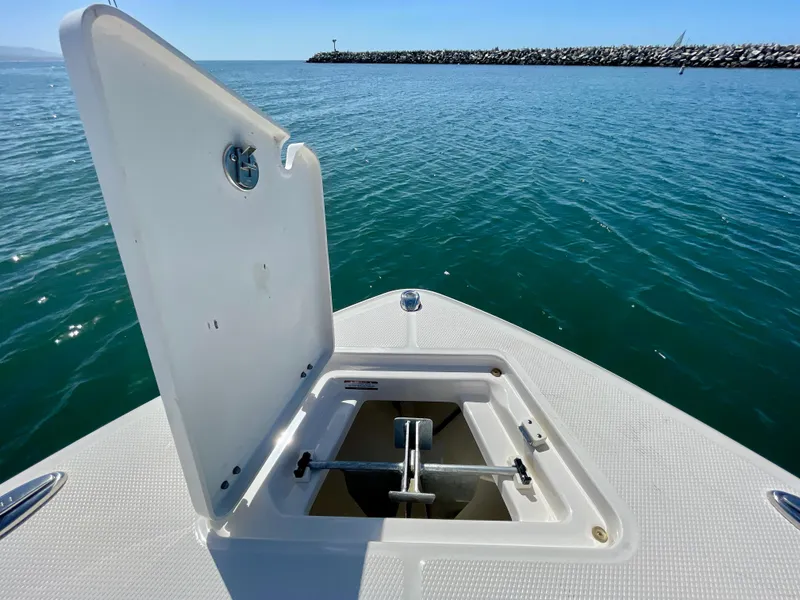 Slide: The Image of 2022 Robalo R230 Center Console boat with open anchor hatch on calm water. - 12