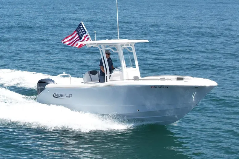 Slide: The Image of 2022 Robalo R230 Center Console boat cruising on open water with American flag. - 2