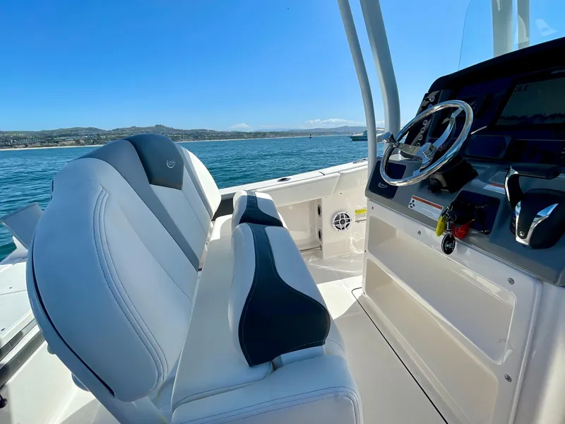 Slide: The Image of 2022 Robalo R230 Center Console boat interior with steering wheel, seats, and ocean view. - 24