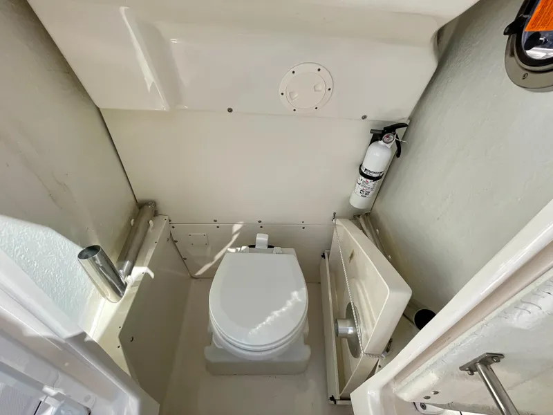 Slide: The Image of 2022 Robalo R230 Center Console boat interior with toilet and fire extinguisher. - 26