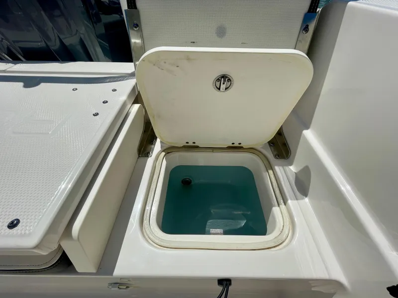 Slide: The Image of 2022 Robalo R230 Center Console livewell with open lid, showcasing interior water storage. - 34