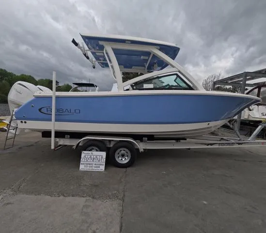 Slide: The Image of 2025 Robalo 257 Dual Console boat on trailer, blue hull, overcast sky. - 1