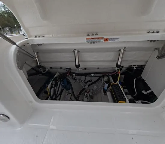 Slide: The Image of 2025 Robalo 257 Dual Console boat storage compartment with hydraulic supports and wiring. - 12