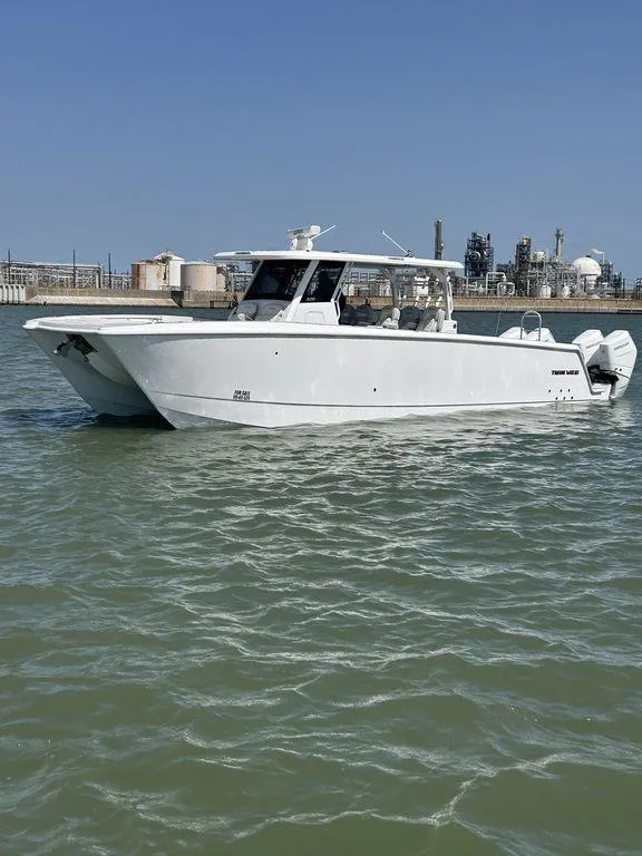 The Image of 2024 Twin Vee 400 GFX boat on water, industrial background, clear sky. - 1