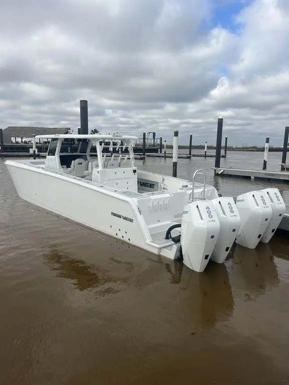 Slide: The Image of 2024 Twin Vee 400 GFX boat with triple engines docked under cloudy skies. - 13