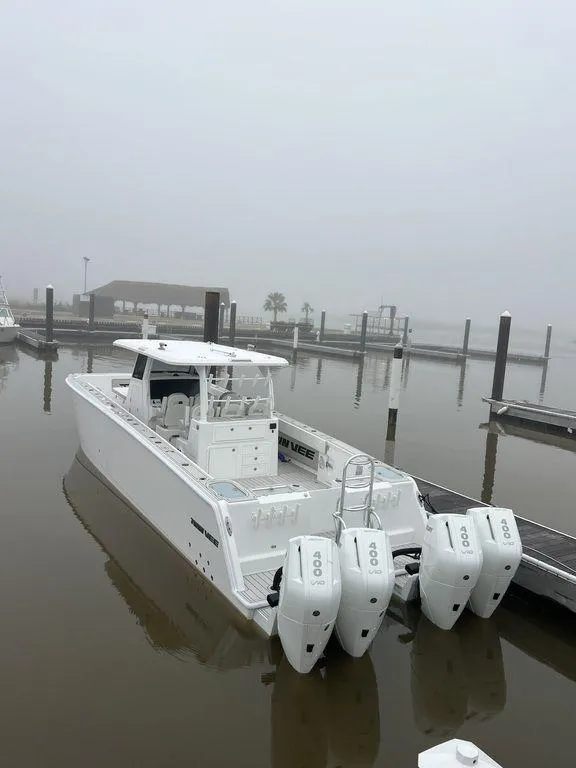 Slide: The Image of 2024 Twin Vee 400 GFX boat docked in a foggy marina with triple outboard engines. - 15
