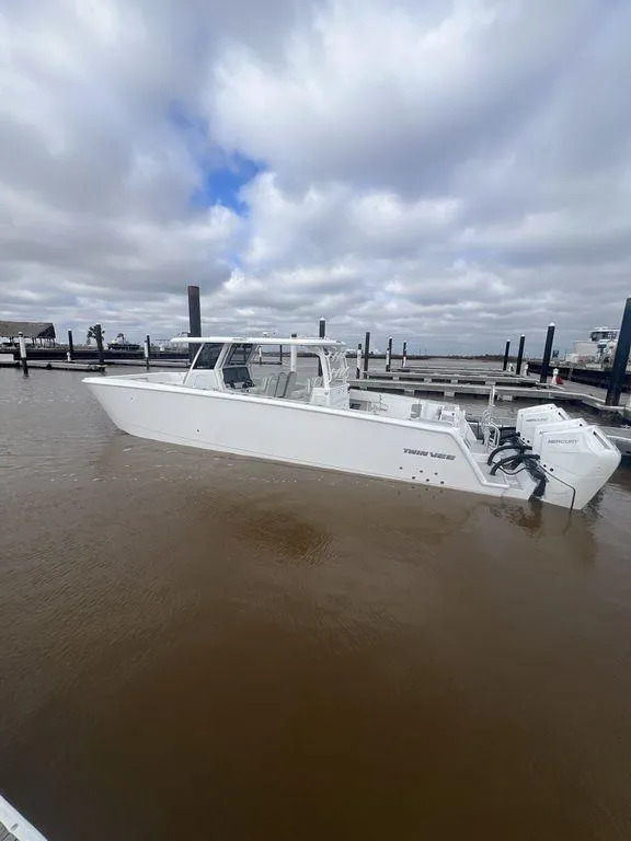 Slide: The Image of 2024 Twin Vee 400 GFX boat docked under cloudy skies. - 19