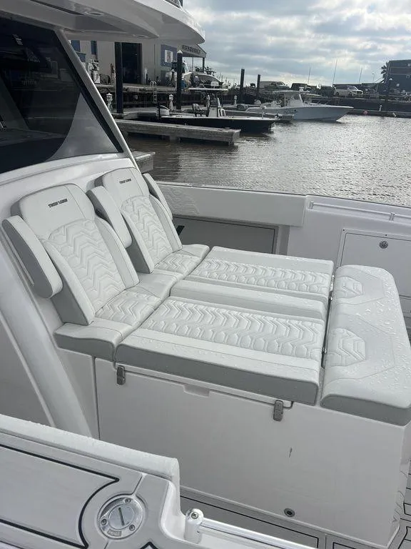 Slide: The Image of 2024 Twin Vee 400 GFX boat with luxurious white seating, docked at a marina. - 25
