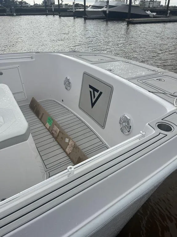 Slide: The Image of 2024 Twin Vee 400 GFX boat interior with sleek design and logo, docked by the water. - 26