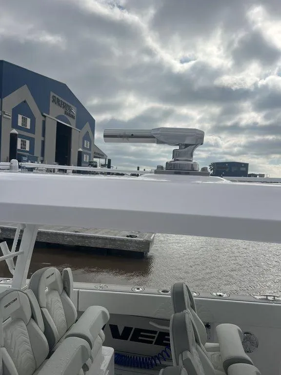 Slide: The Image of 2024 Twin Vee 400 GFX boat with sleek design, docked near a marina under cloudy skies. - 33