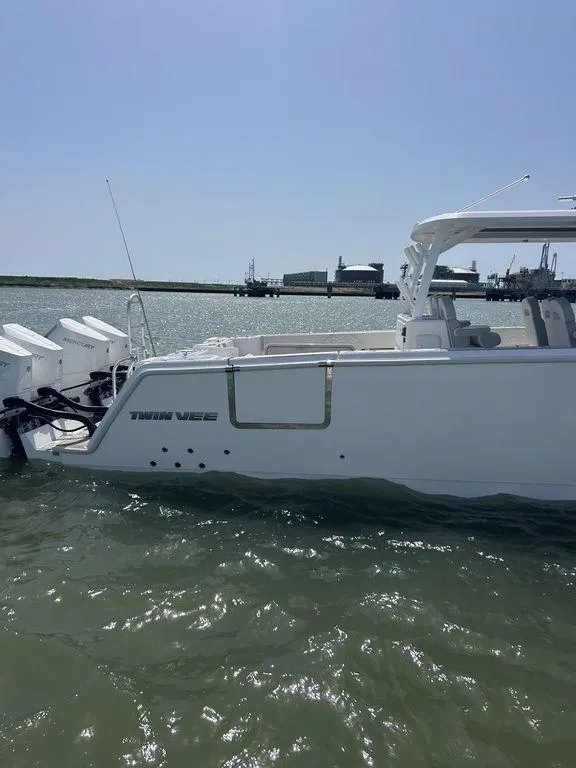 Slide: The Image of 2024 Twin Vee 400 GFX boat on water, side view, clear sky background. - 7